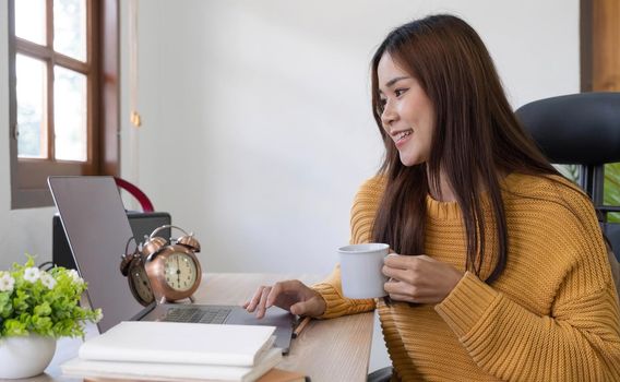 Profile side photo of smart chinese girl ceo expert sit desk work remote laptop texting typing report hold beverage mug in house indoors.