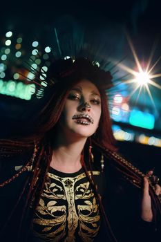 Female with skeleton makeup at a Halloween party looks at camera. All Saints' Night. Celebration in a nightclub. Woman in creepy costume of Mexican goddess of death.