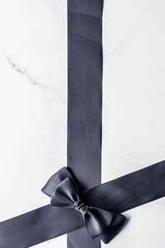 Holiday gift, decoration and sale promotion concept - Black silk ribbon and bow on marble background, flatlay