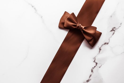 Holiday gift, decoration and sale promotion concept - Chocolate brown silk ribbon on marble background, flatlay