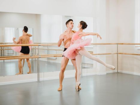 Rehearsal in the ballet hall or studio with minimalism interior. Young professional sensual dancer's couple in beautiful costumes dancing together.