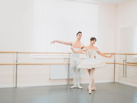 Professional, emotional ballet dancers practicing in the gym or hall with minimalism interior. Couple dancing a sensual dance before performance.