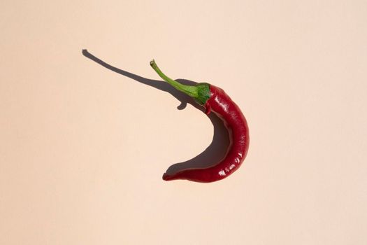 red hot pepper on a beige background with a hard shadow. High quality photo