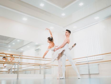 Professional, emotional ballet dancers practicing in the gym or hall with minimalism interior. Couple dancing a sensual dance before performance.