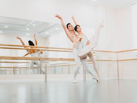 Professional, emotional ballet dancers practicing in the gym or hall with minimalism interior. Couple dancing a sensual dance before performance.