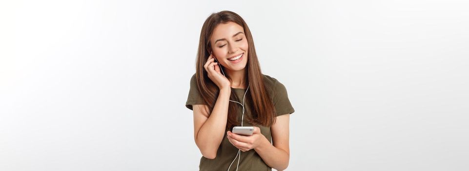 Portrait of a cheerful cute woman listening music in headphones and dancing isolated on a white background