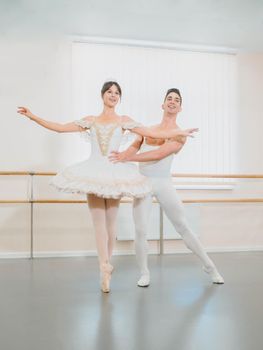 Rehearsal in the ballet hall or studio with minimalism interior. Young professional sensual couple in beautiful costumes dancing together.