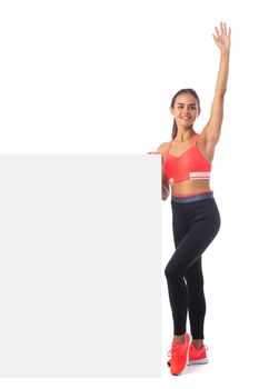 Healthy hispanic fitness girl with arm raised holding blank banner isolated on white background