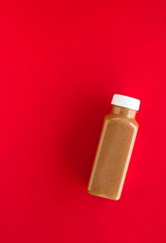 Detox, diet and healthy lifestyle concept - Chocolate banana smoothie bottle on red, flatlay