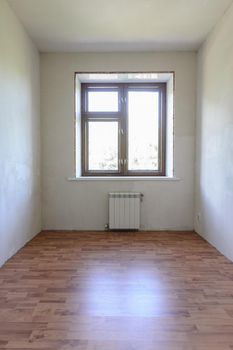 View of the window in a small room after renovation, wood-effect laminate is laid on the floor a