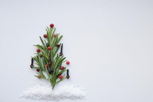 Food Christmas background with green Rosemary twigs as Christmas tree. Minimalist Flat lay of herbs and spices in shape of a Christmas tree, Top view, Christmas concept.