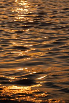 Ripple sea ocean water surface with golden sunset light. Sea waves close up