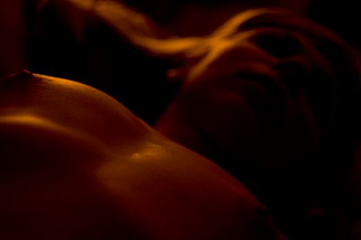Young woman posing in the dark with naked breasts