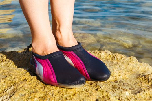 Swimming neoprene shoes in water on beach. 