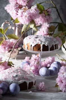 beautiful Easter cake on the table, and colored eggs, homemade cakes, still life with a silver teapot on a background of pink sakura. High quality photo