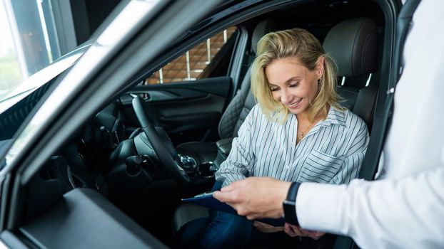 Happy caucasian woman signing a contract to buy a car