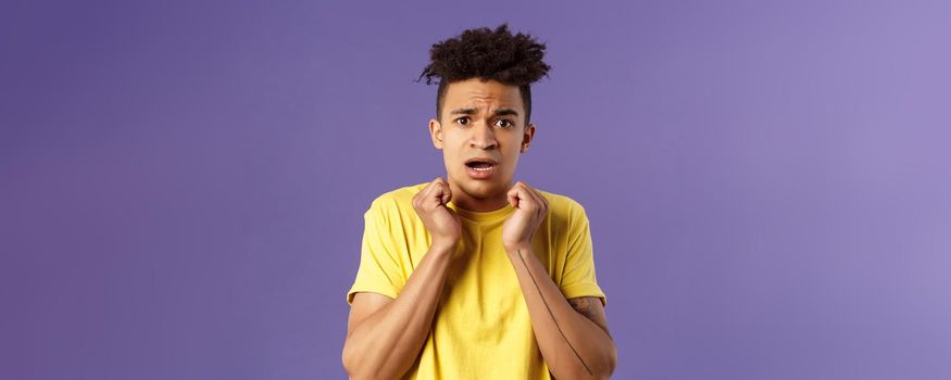 Close-up portrait of timid, insecure and worried young hispanic guy worried for own safety being in house alone, hear scary noises from downstairs, trembling fear, look concerned and afraid.