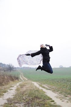 Portrait of jumping young blonde woman on field