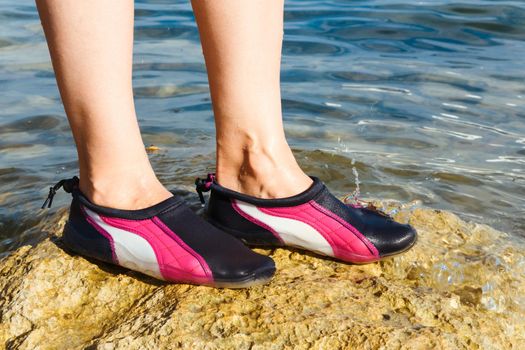 Swimming neoprene shoes in water on beach. 