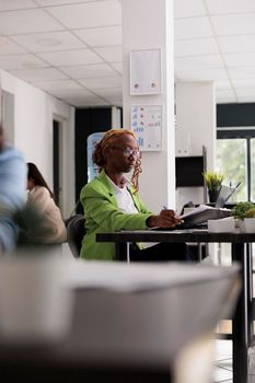 Employee working with business documents, analyzing financial report in office open space, woman sitting at workplace desk. Young woman looking at company papers, side view