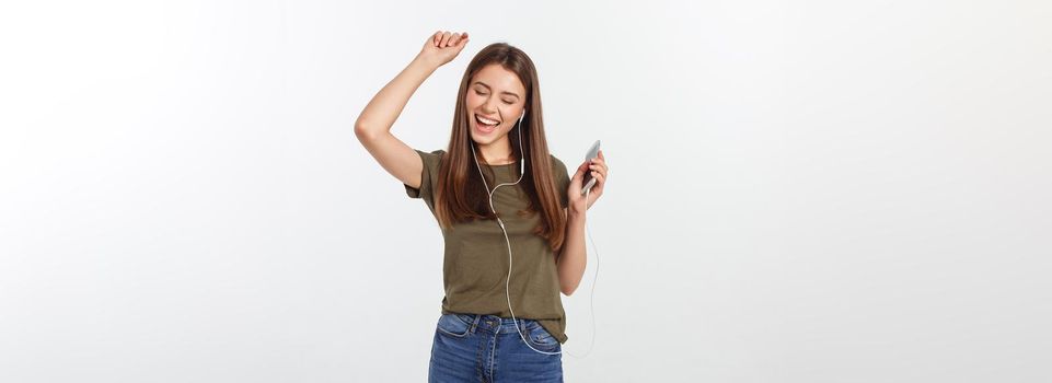 Portrait of a cheerful cute woman listening music in headphones and dancing isolated on a white background