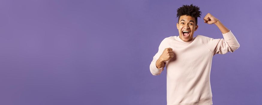 Portrait of excited happy man seeing his team scored goal on sports tv channel, chanting raise one hand in triumph, screaming in joy and happiness, celebrating victory, placed right bet.