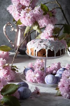 beautiful Easter cake on the table, and colored eggs, homemade cakes, still life with a silver teapot on a background of pink sakura. High quality photo