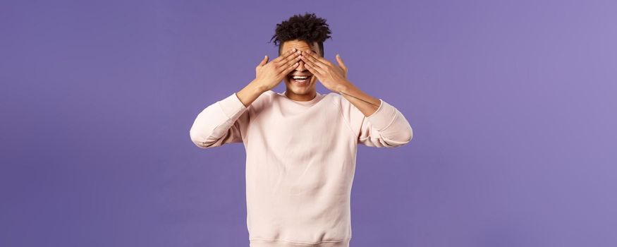 Portrait of surprised and excited, amused happy birthday guy close eyes and count ten to see what friends brought as gift, anticipating present, awaiting with cheerful expression, purple background.