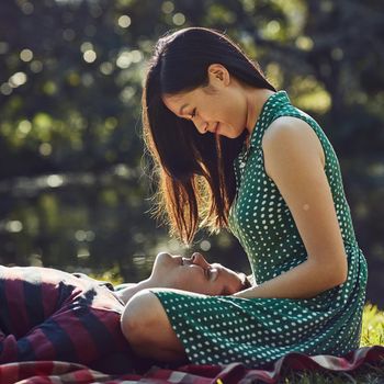 The perfect spot for some romance. an affectionate young couple relaxing together on a picnic blanket in the park