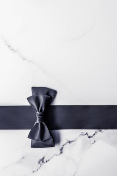 Holiday gift, decoration and sale promotion concept - Black silk ribbon and bow on marble background, flatlay