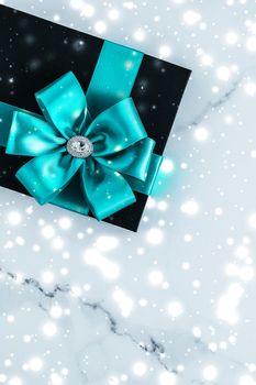 New Years Eve celebration, wrapped luxury boxes and cold season concept - Winter holiday gifts with emerald silk bow and glowing snow on frozen marble background, Christmas presents surprise