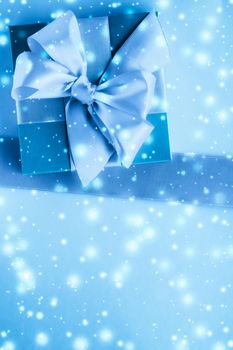 New Years Eve celebration, wrapped luxury boxes and cold season concept - Winter holiday gifts and glowing snow on frozen blue background, Christmas presents surprise