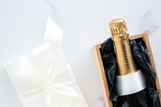 Wedding celebration, lifestyle and luxury present concept - A champagne bottle and a gift box on marble