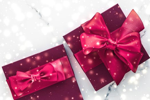 New Years Eve celebration, wrapped luxury boxes and cold season concept - Winter holiday gifts with cherry silk bow and glowing snow on frozen marble background, Christmas presents surprise