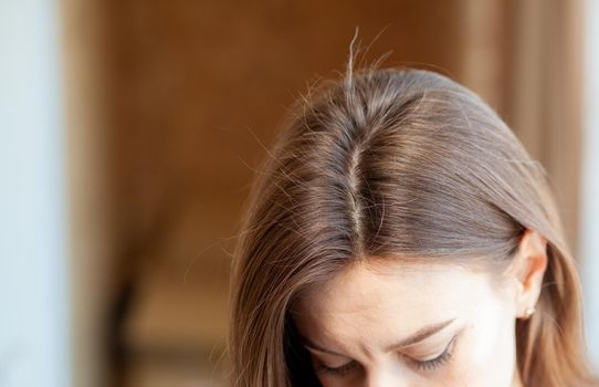 Parting of women's hair on the head. Hair care and care. Closeup of a woman's head with parted gray hair regrown roots becouse of quarantine