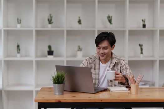 Asian man using laptop computer working at office. Creative and new idea concpet.