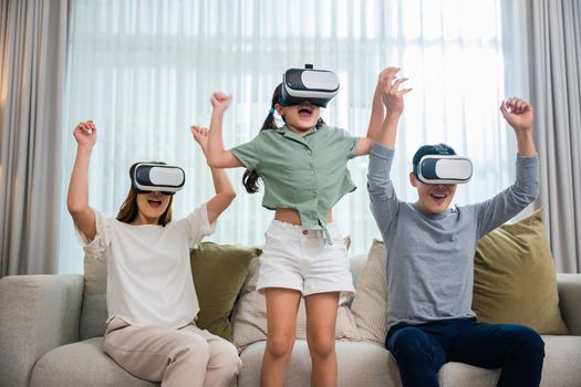 Asian family wear vr glasses headsets sitting on sofa in living room, game entertainment innovation technology, Happy family have mother father and daughter watching movie or playing video game