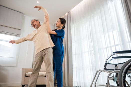 Old senior man enjoys training with physiotherapist for outstretched arms at home, Asian physical therapist patient nursing helping elderly exercising arm stretch, Rehabilitation of disabled concept