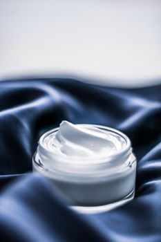 Beauty, anti-age cosmetics and skincare concept - Luxury face cream jar on a dark blue silk