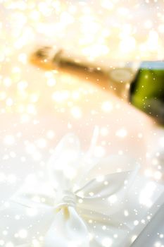 Christmas time, happy holidays and luxury present concept - New Years Eve holiday champagne bottle and a gift box and shiny snow on marble background