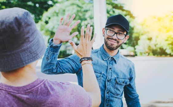 Back view of two smiling friends shaking hands on the street. Two smiling friends shaking hands in a park. Concept of two friends greeting each other with a handshake on the street