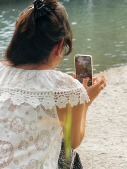 asian hindi woman enjoying the river a cloudy day checking photos on smart phone