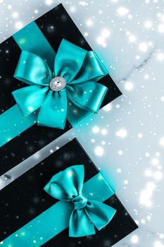 New Years Eve celebration, wrapped luxury boxes and cold season concept - Winter holiday gifts with emerald silk bow and glowing snow on frozen marble background, Christmas presents surprise