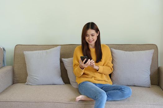 woman sitting on sofa at home ready to use mobile phone.