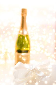 Christmas time, happy holidays and luxury present concept - New Years Eve holiday champagne bottle and a gift box and shiny snow on marble background