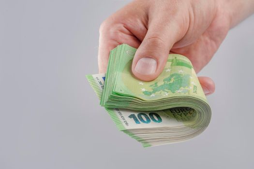 salary in Europe. Increase or decrease of wages in the European Union. A man's hand holds a stack of 100 euro banknotes