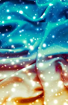 Winter fashion, shiny fabric and glamour style concept - Magic holiday blue and gold soft silk flatlay background texture with glowing snow, luxury beauty abstract backdrop