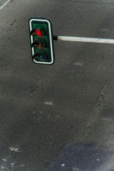 High angle day view of overhead hanging traffic light on a pole above an empty asphalt road.