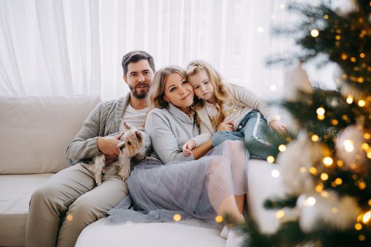 Happy family: mom, dad and pet. Family in a bright New Year's interior with a Christmas tree.