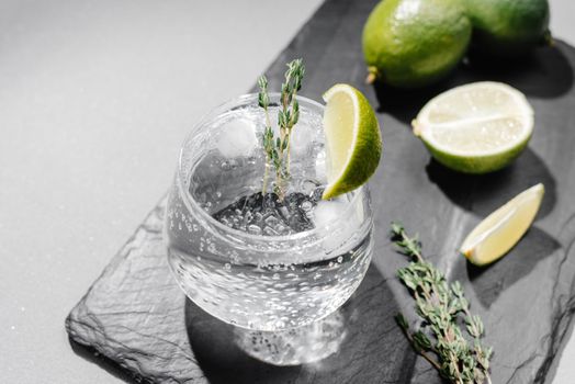 Tonic with lime and thyme. Cocktail on a gray background. Flashy food.